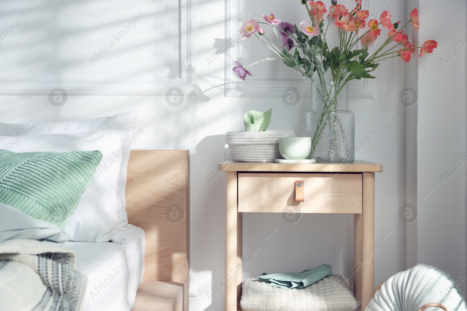 Photo of Bedside table with different decor near bed indoors