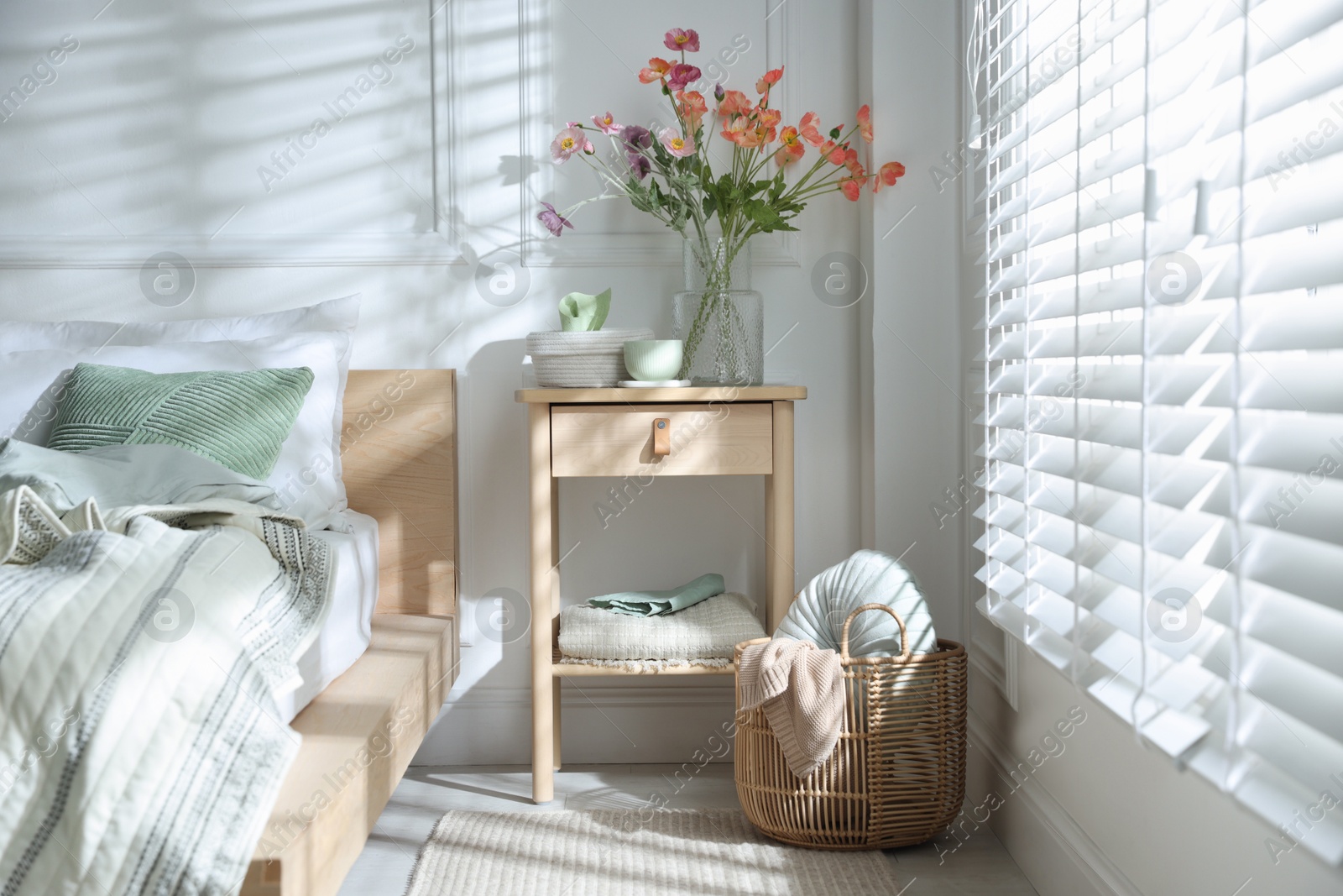 Photo of Bedside table with different decor near bed indoors