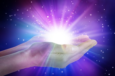 Image of Woman creating bright light against black background, closeup. Aura, spiritual practice