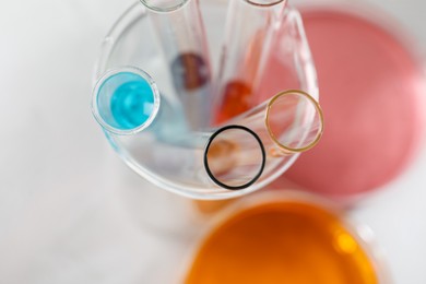 Photo of Test tubes with different samples and Petri dishes on table, top view. Solution chemistry