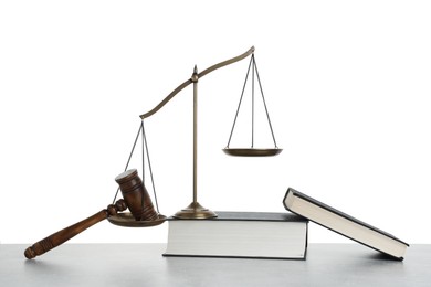 Photo of Golden scales of justice, books and gavel on light grey table against white background