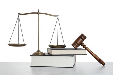 Photo of Golden scales of justice, books and gavel on light grey table against white background