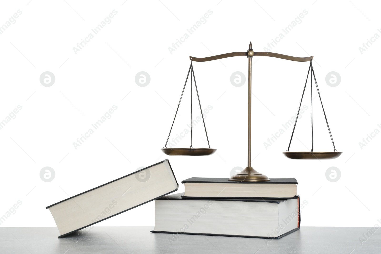Golden scales of justice and books on light grey table against white background Photo of Golden scales of justice and books on light grey table against white background