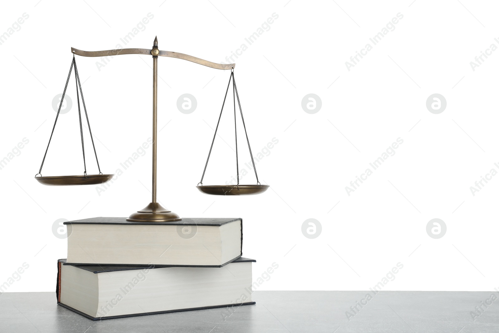 Photo of Golden scales of justice and books on light grey table against white background