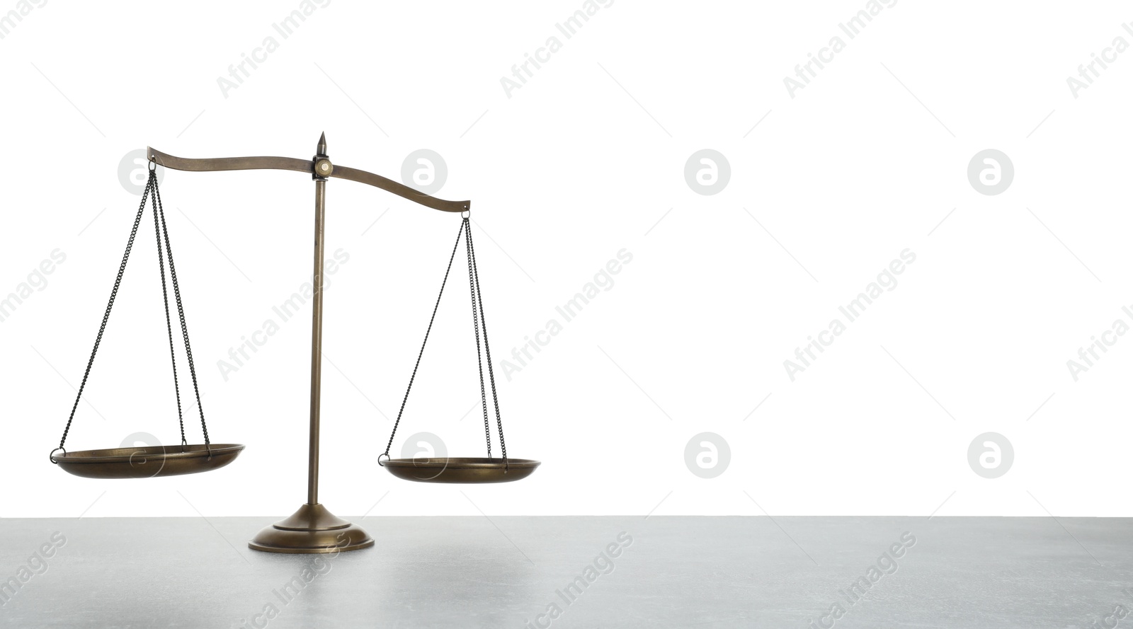 Photo of Golden scales of justice on light grey table against white background