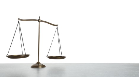 Photo of Golden scales of justice on light grey table against white background