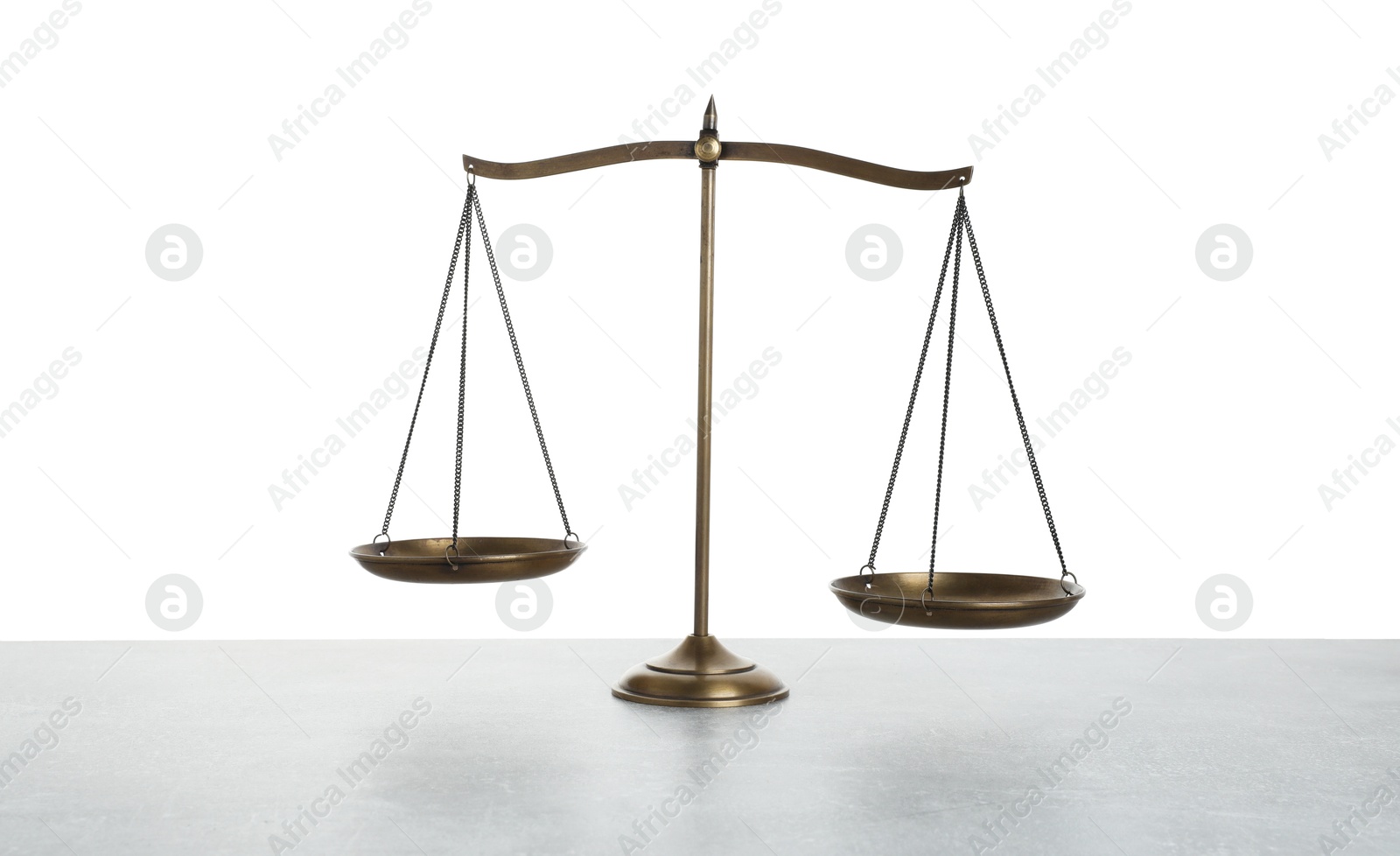 Golden scales of justice on light grey table against white background Photo of Golden scales of justice on light grey table against white background