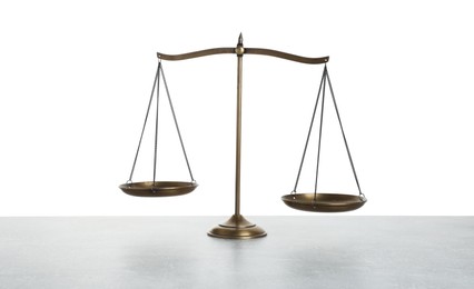 Photo of Golden scales of justice on light grey table against white background