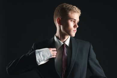 Photo of Handsome young man wearing stylish suit on black background