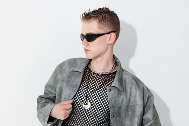 Photo of Handsome young man wearing stylish jacket and sunglasses on white background