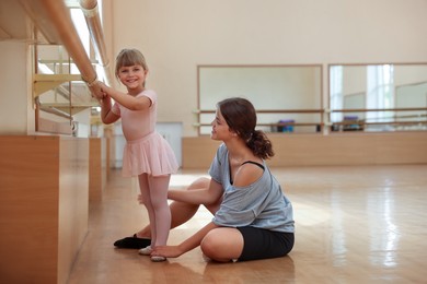 Photo of Smiling little girl and her teacher training in barre studio