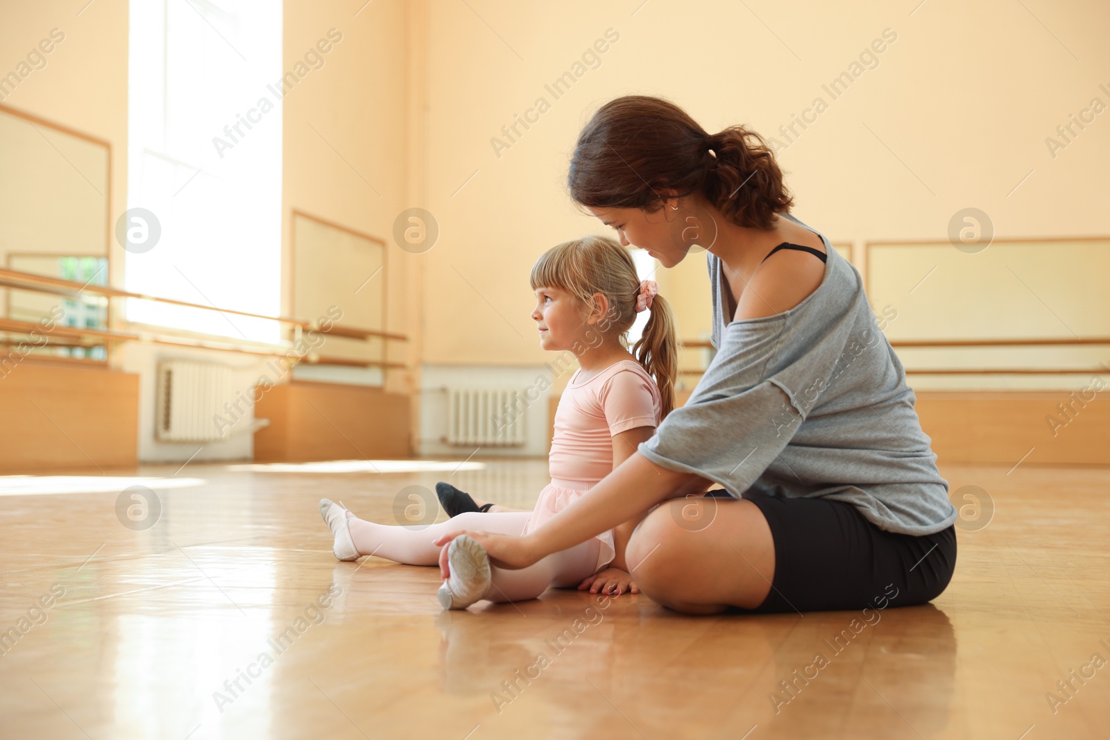 Ballet teacher working with little girl on floor in dance class Photo of Ballet teacher working with little girl on floor in dance class