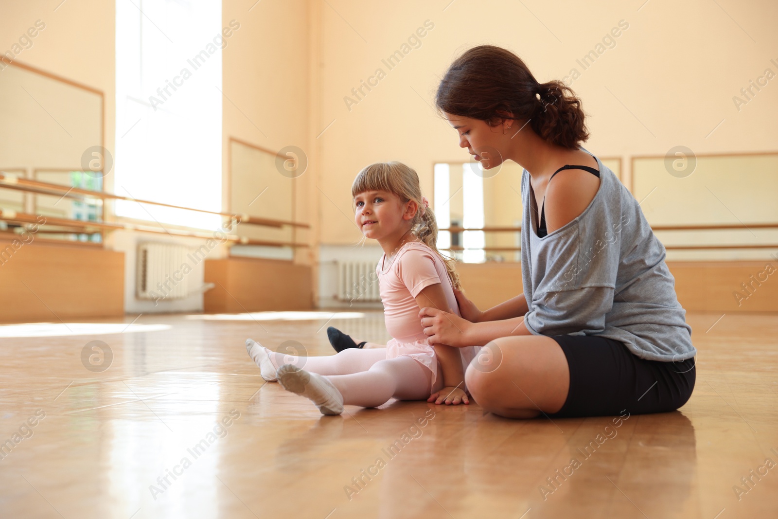 Ballet teacher working with little girl on floor in dance class Photo of Ballet teacher working with little girl on floor in dance class