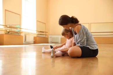 Photo of Ballet teacher working with little girl on floor in dance class