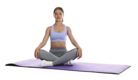Photo of Teenage girl in sportswear stretching on mat against white background
