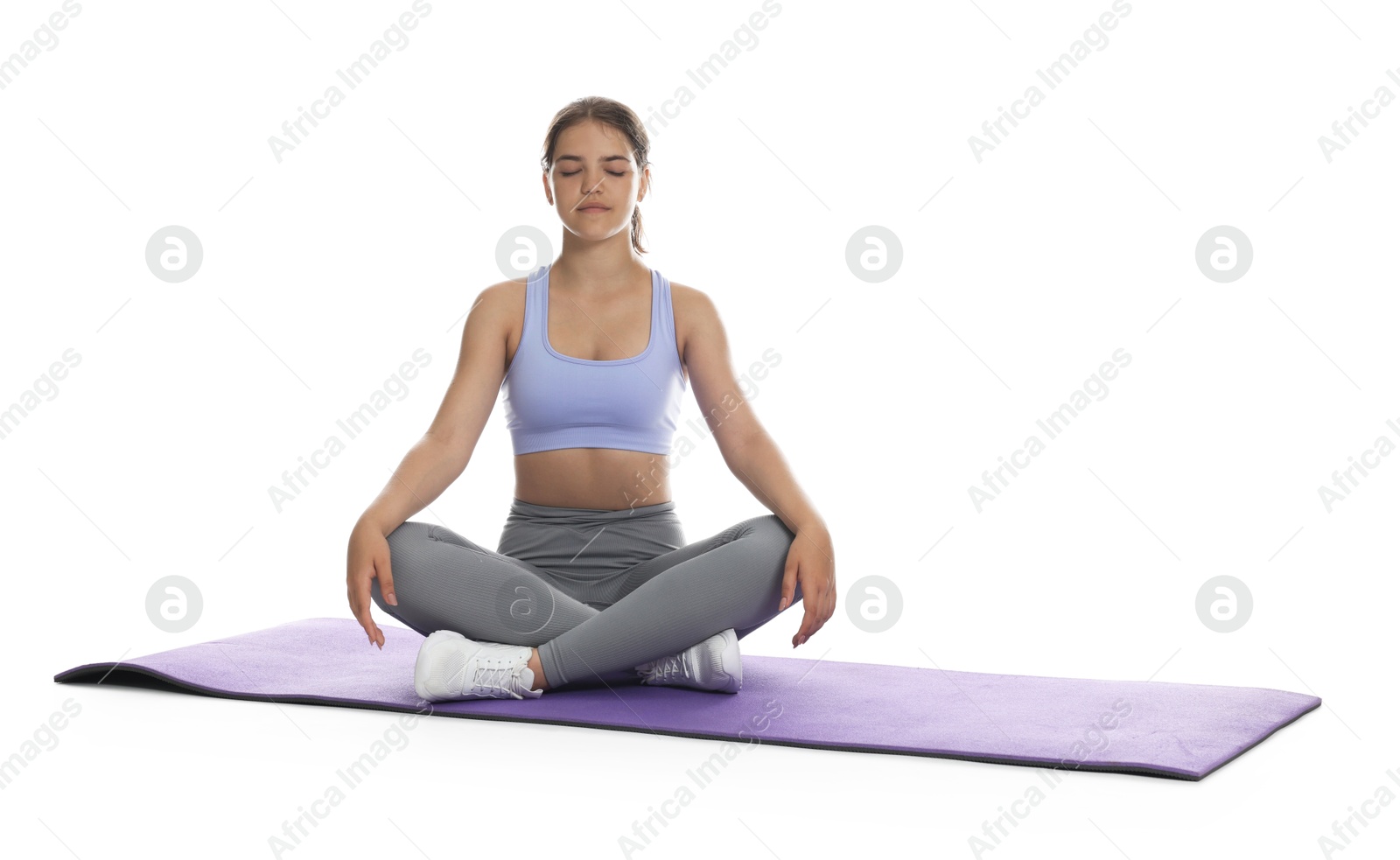 Teenage girl in sportswear stretching on mat against white background Photo of Teenage girl in sportswear stretching on mat against white background