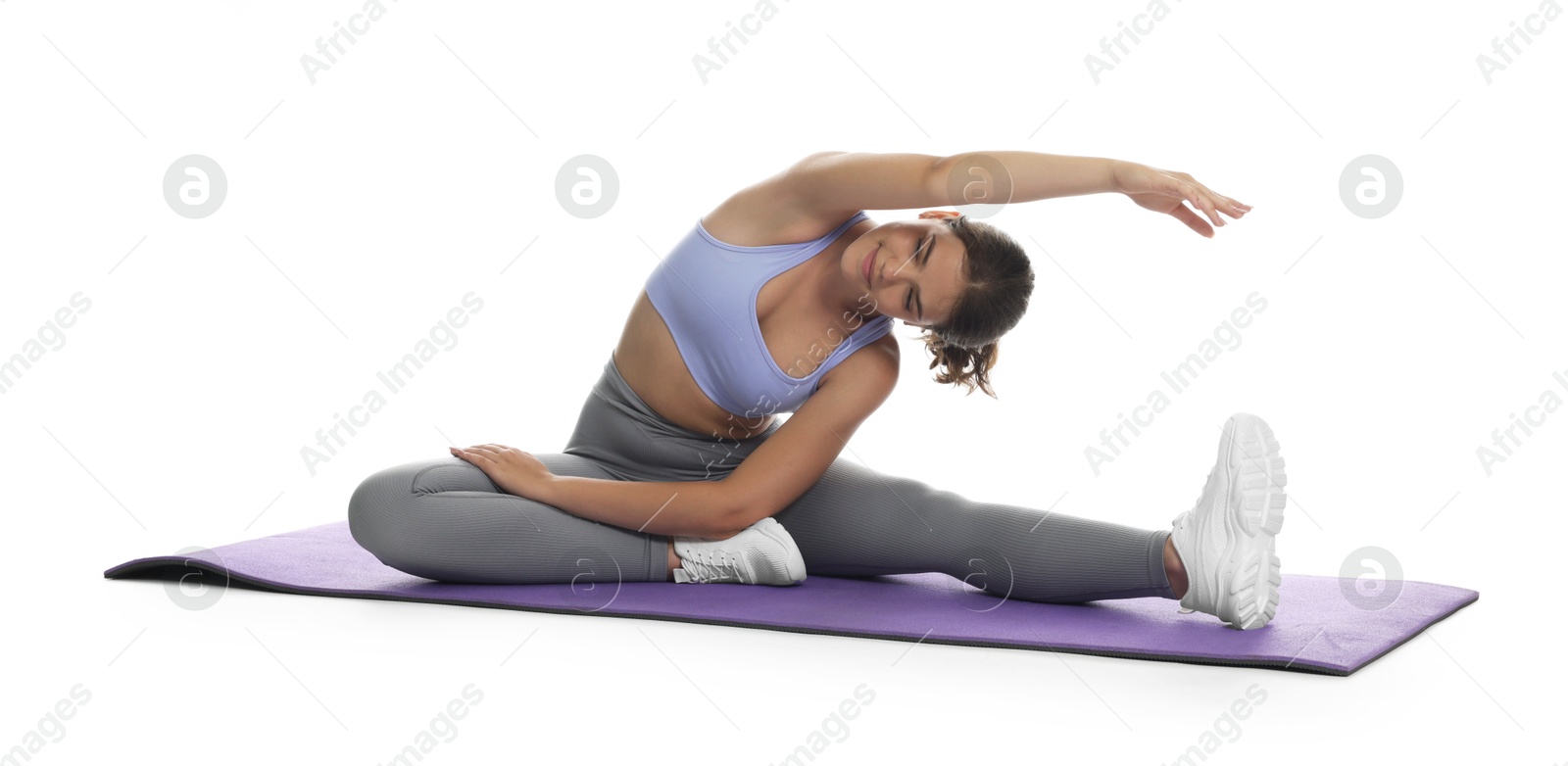 Teenage girl in sportswear stretching on mat against white background Photo of Teenage girl in sportswear stretching on mat against white background
