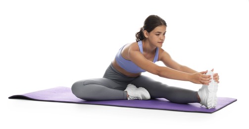 Photo of Teenage girl in sportswear stretching on mat against white background