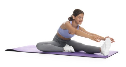 Photo of Teenage girl in sportswear stretching on mat against white background