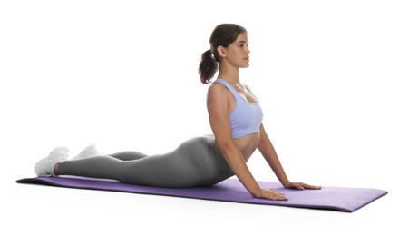 Photo of Teenage girl in sportswear stretching on mat against white background