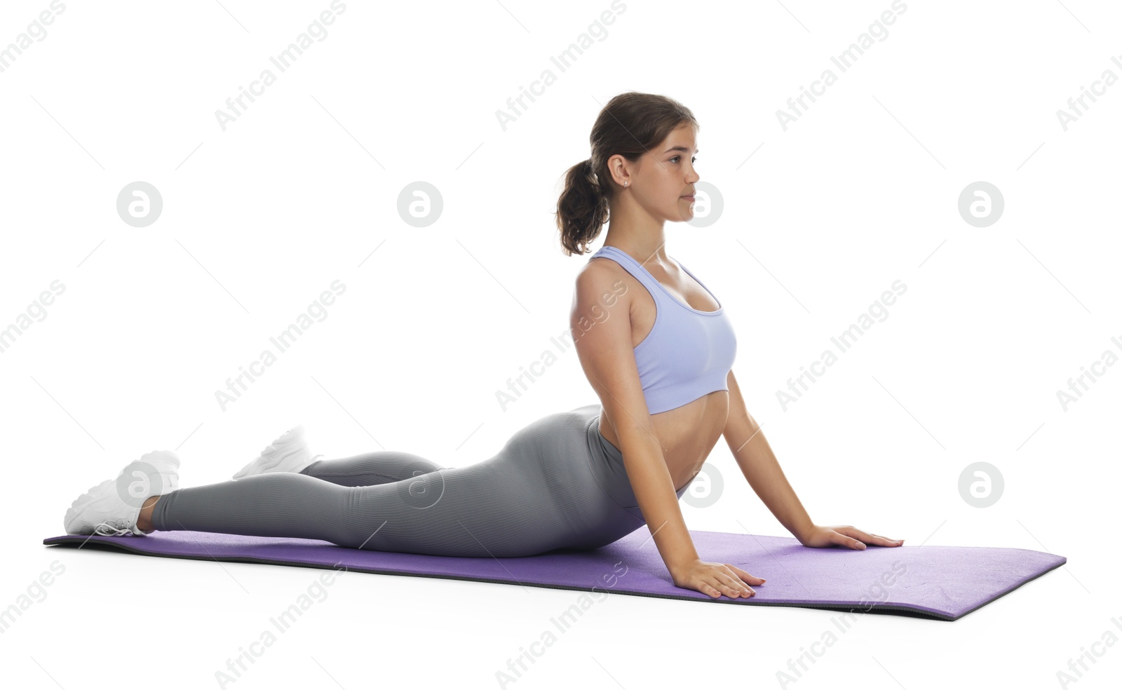 Photo of Teenage girl in sportswear stretching on mat against white background