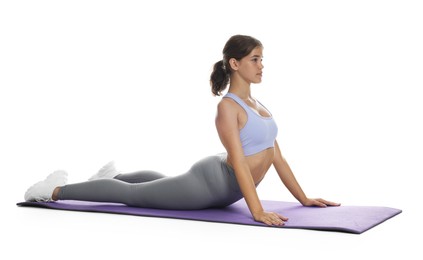 Photo of Teenage girl in sportswear stretching on mat against white background