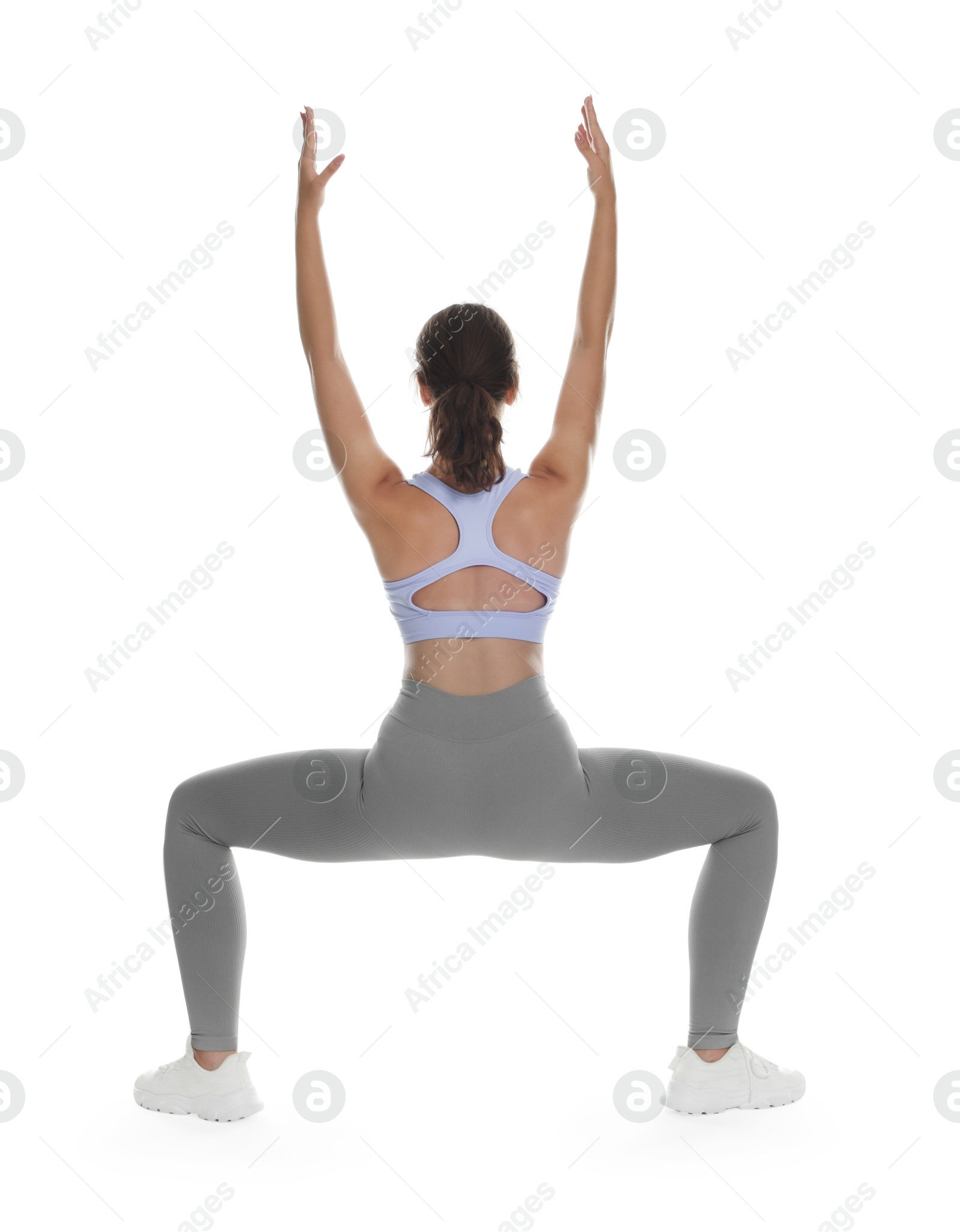 Photo of Teenage girl in sportswear stretching on white background, back view
