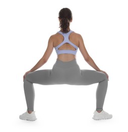 Photo of Teenage girl in sportswear stretching on white background, back view