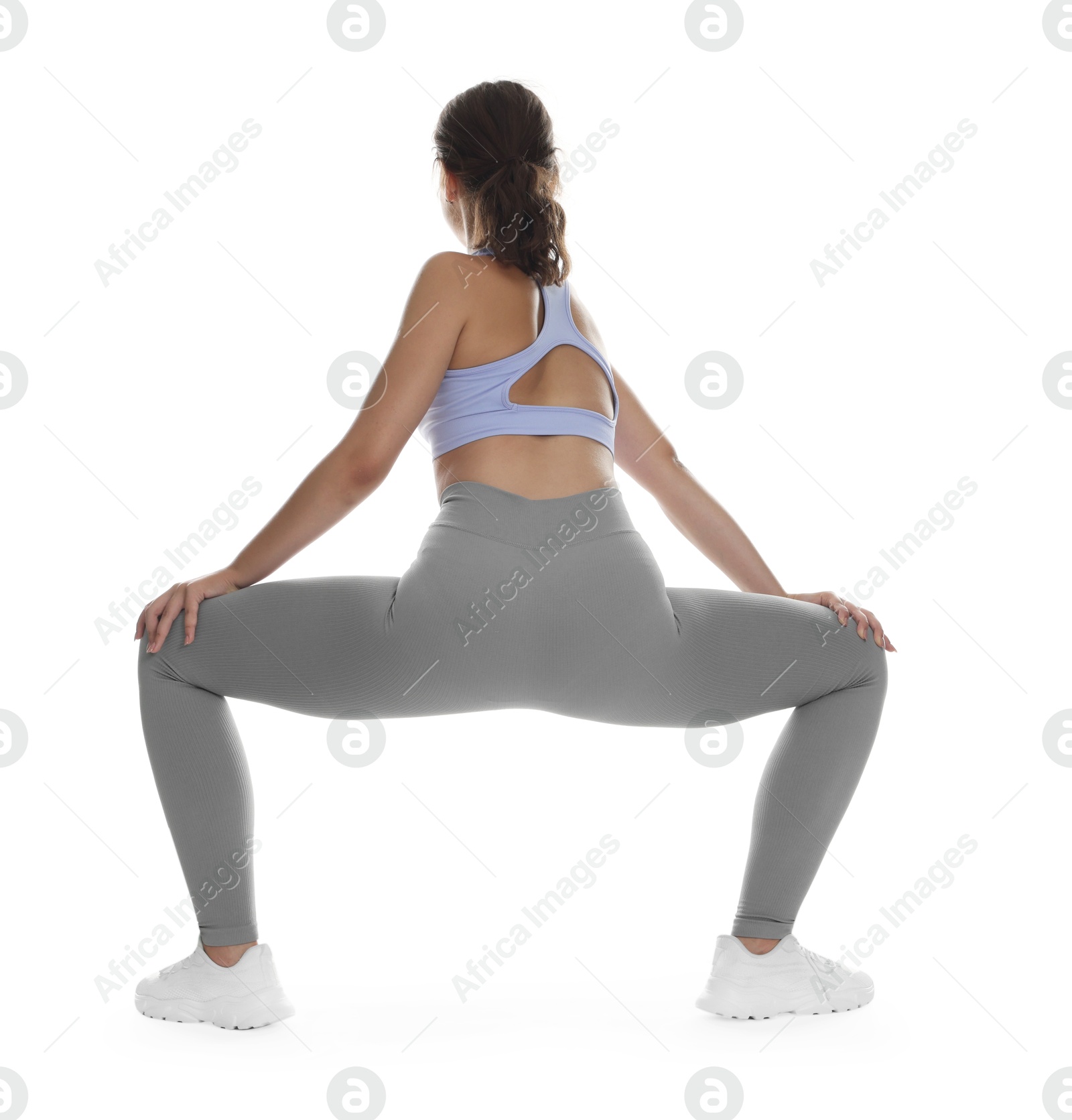 Photo of Teenage girl in sportswear stretching on white background, back view