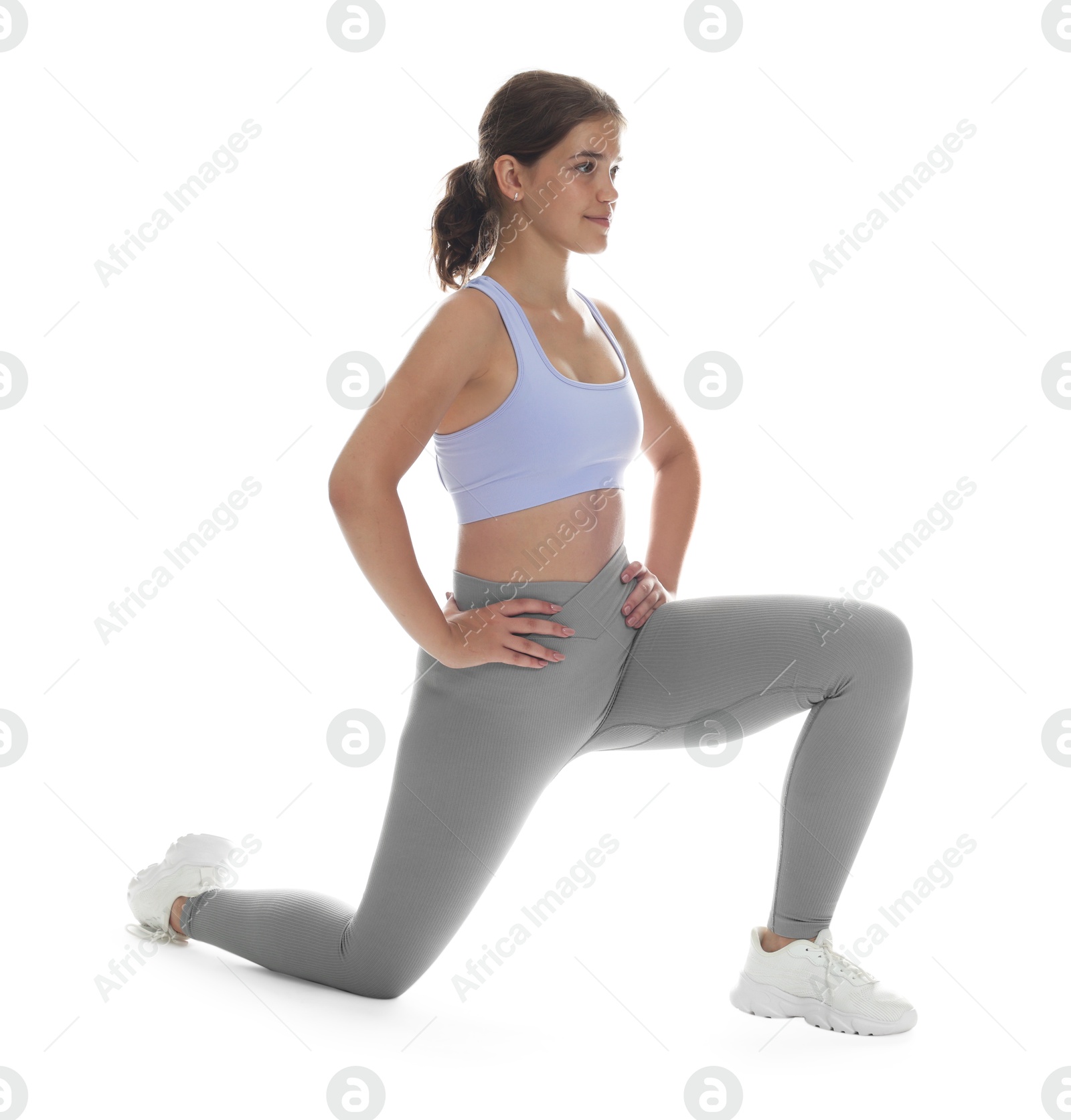 Photo of Teenage girl in sportswear stretching on white background