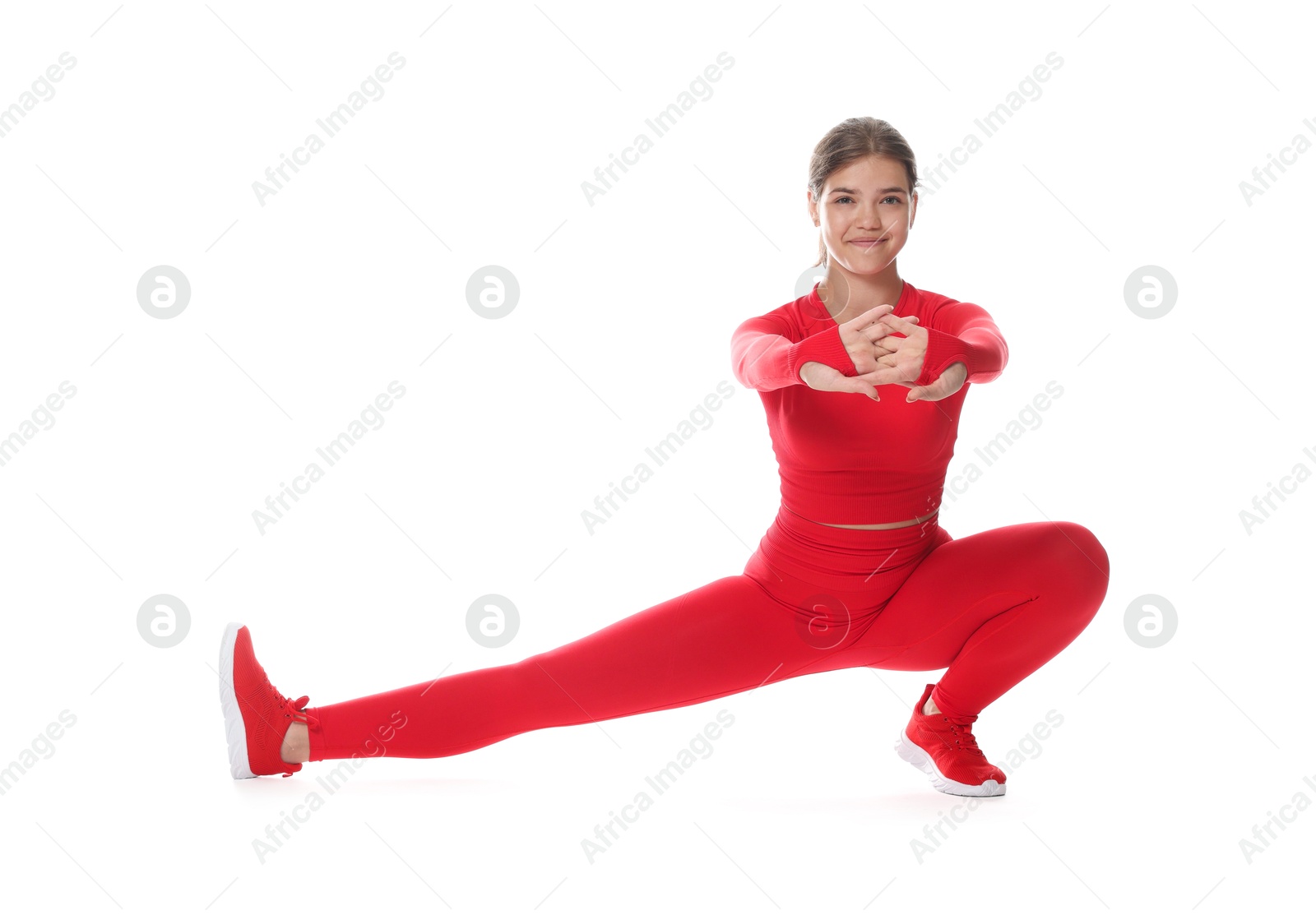Photo of Teenage girl in sportswear stretching on white background