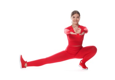Photo of Teenage girl in sportswear stretching on white background
