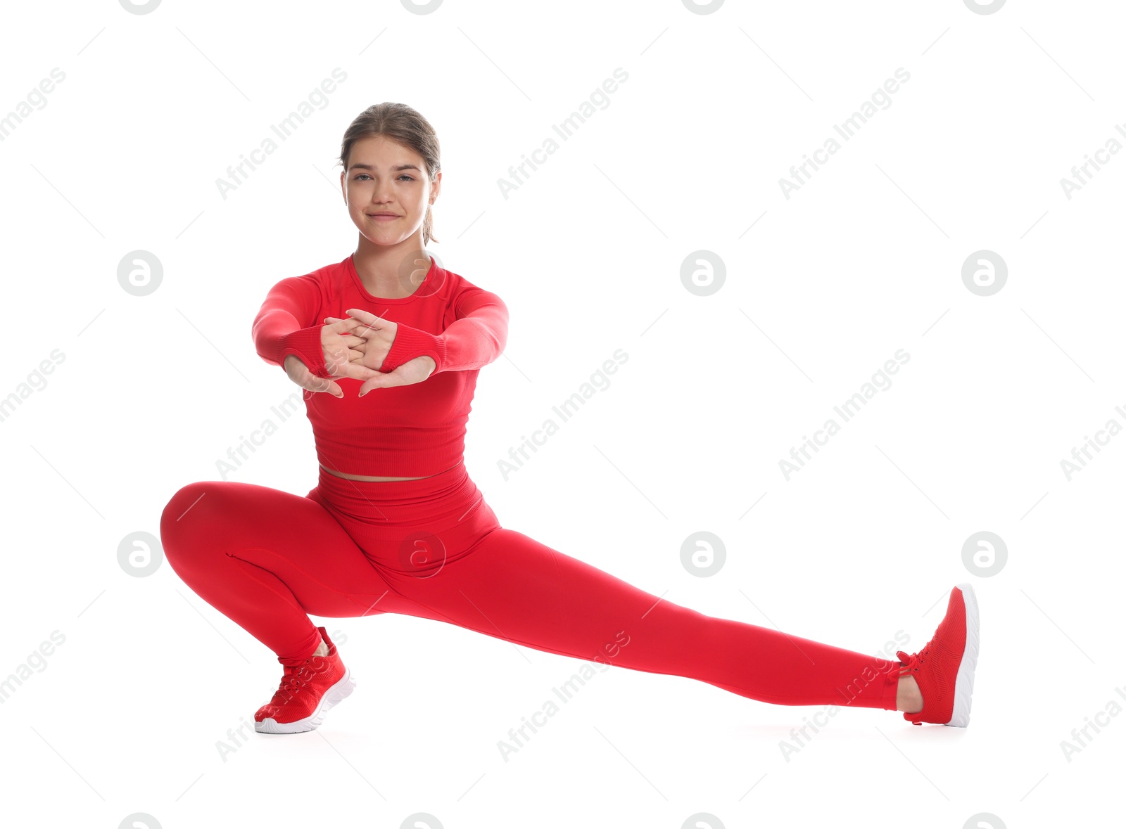 Photo of Teenage girl in sportswear stretching on white background