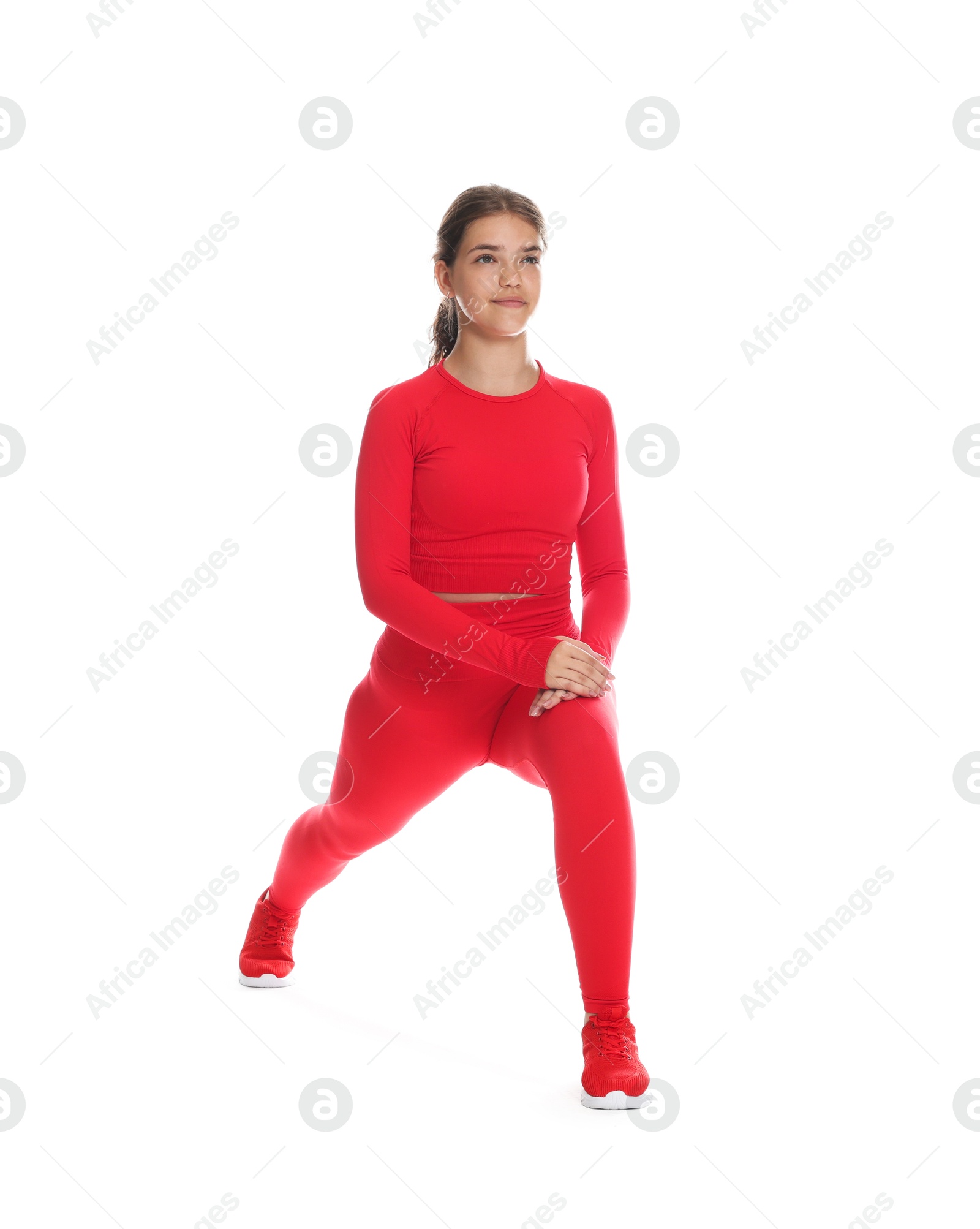 Photo of Teenage girl in sportswear stretching on white background
