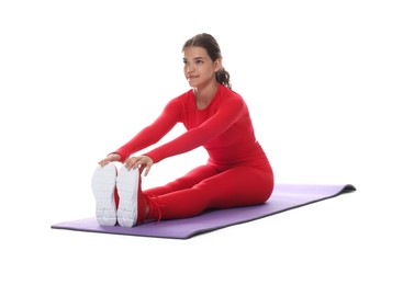 Photo of Teenage girl in sportswear stretching on mat against white background