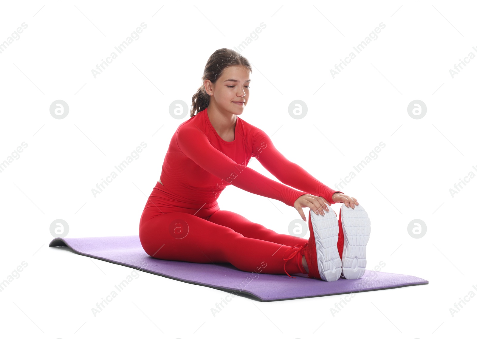 Photo of Teenage girl in sportswear stretching on mat against white background
