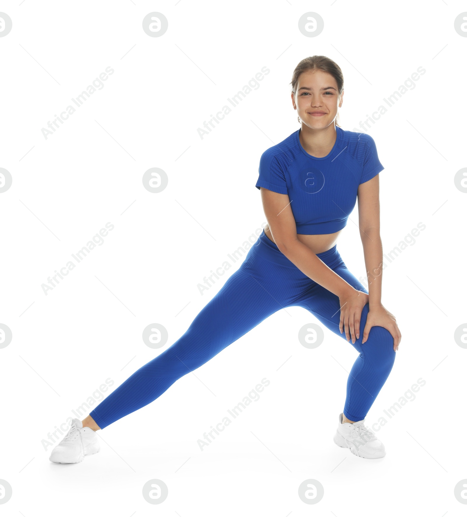 Photo of Teenage girl in sportswear stretching on white background