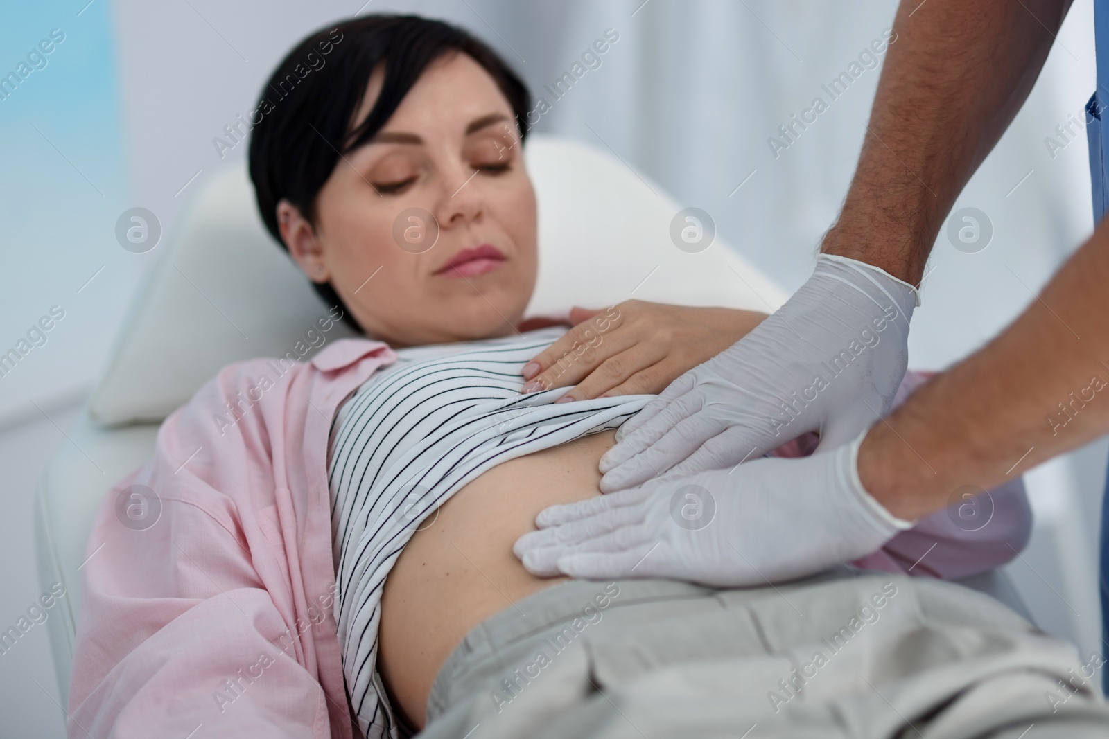 Photo of Gastroenterologist examining patient's stomach in clinic, closeup