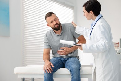 Photo of Gastroenterologist consulting patient with stomach pain in clinic