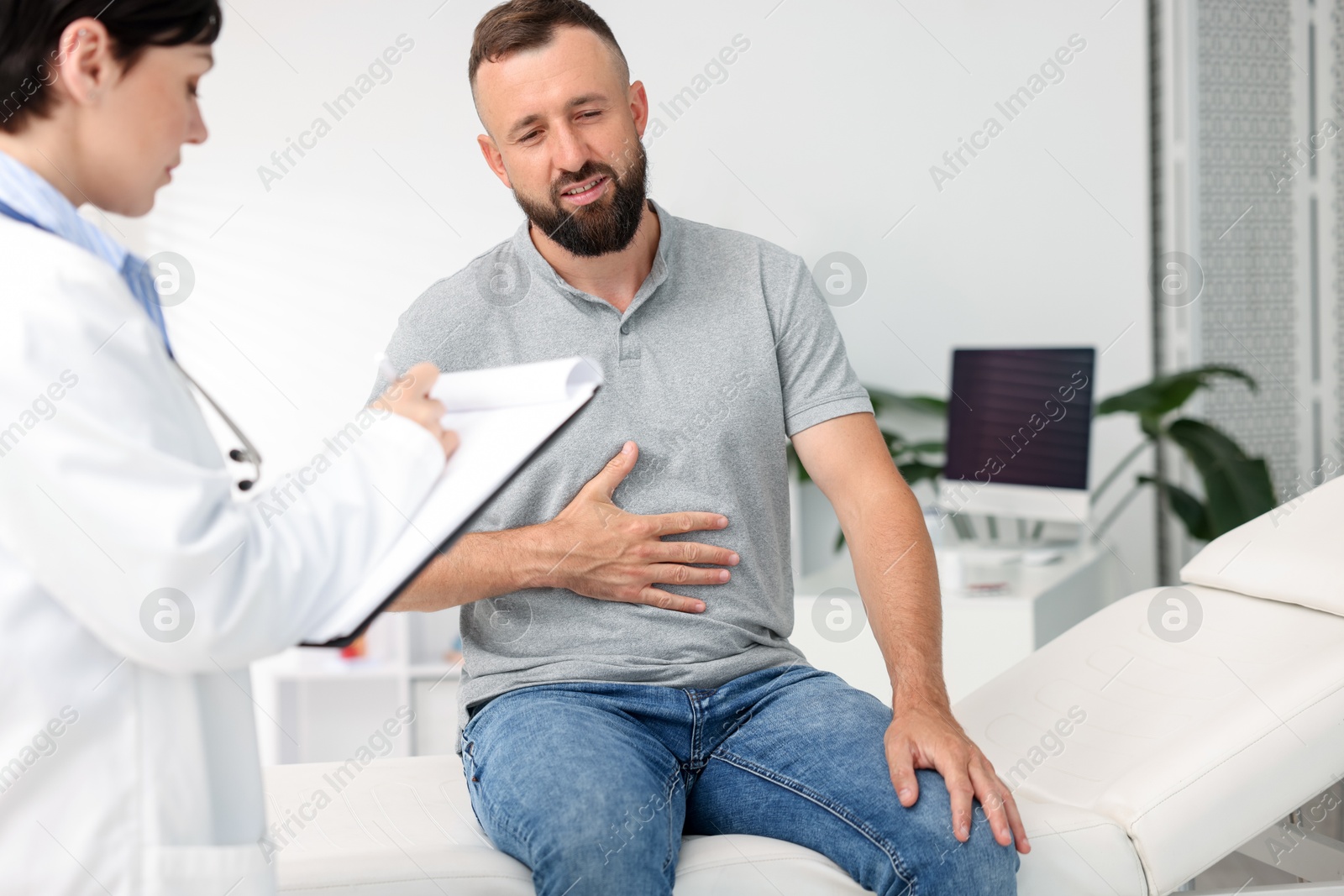 Photo of Gastroenterologist consulting patient with stomach pain in clinic