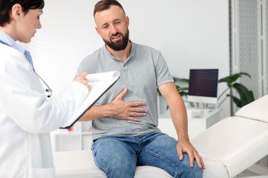 Photo of Gastroenterologist consulting patient with stomach pain in clinic