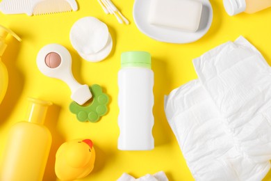 Photo of Baby accessories and cosmetic products on yellow background, flat lay