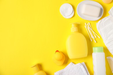 Photo of Baby accessories and cosmetic products on yellow background, flat lay. Space for text