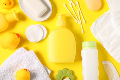 Photo of Baby accessories and cosmetic products on yellow background, flat lay