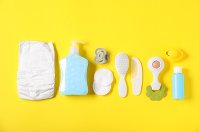 Photo of Baby accessories and cosmetic products on yellow background, flat lay