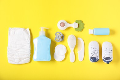 Photo of Baby accessories and cosmetic products on yellow background, flat lay