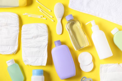 Photo of Baby accessories and cosmetic products on yellow background, flat lay