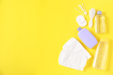 Photo of Baby accessories and cosmetic products on yellow background, flat lay. Space for text