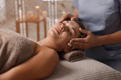Photo of Beautiful woman receiving facial massage on couch in spa salon, closeup
