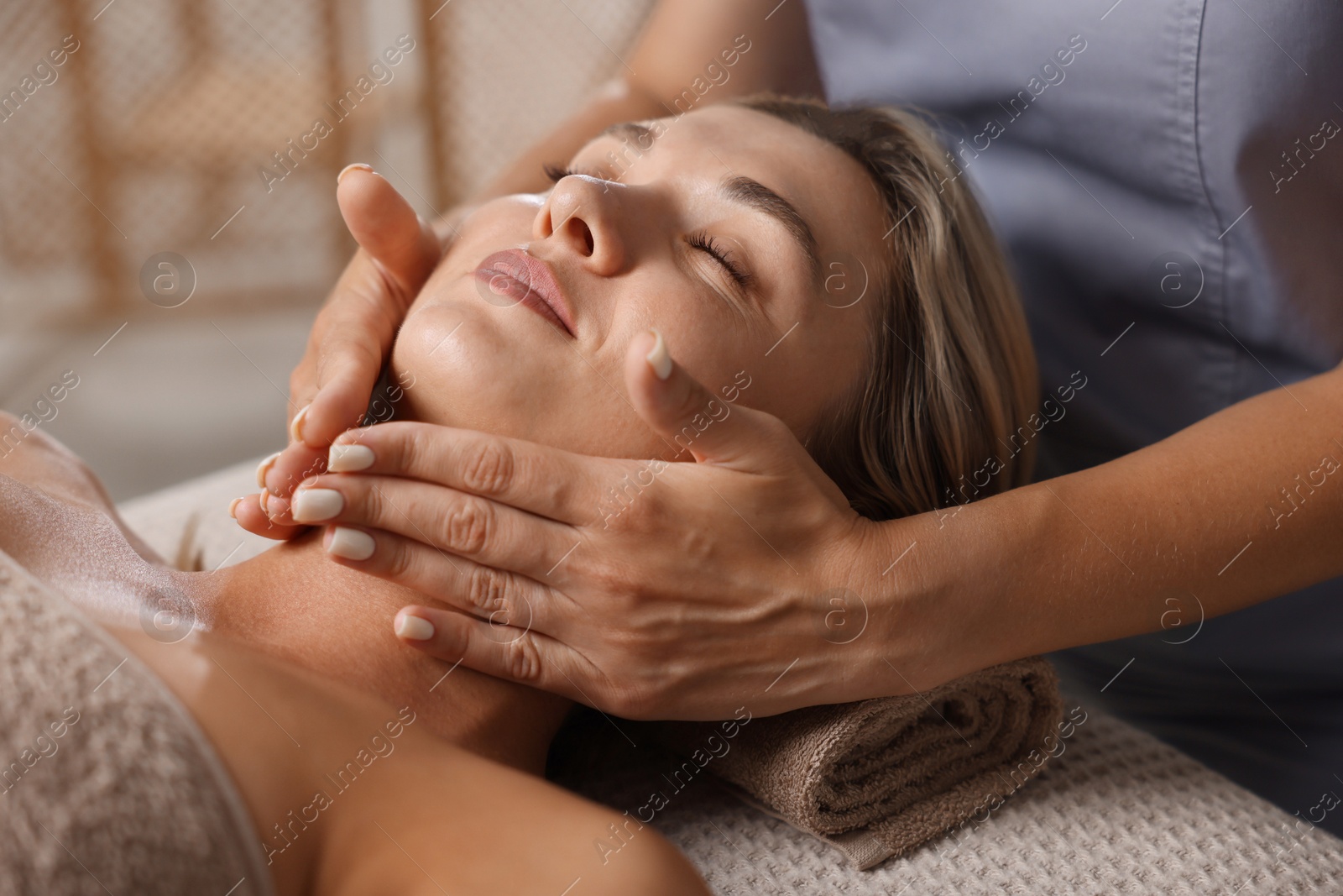 Beautiful woman receiving facial massage on couch in spa salon, closeup Photo of Beautiful woman receiving facial massage on couch in spa salon, closeup